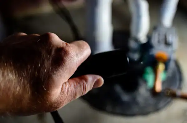 A hand holding a black cable, seemingly guiding power and precision like a sump pump installation, reaches toward a robotic figure on the platform.