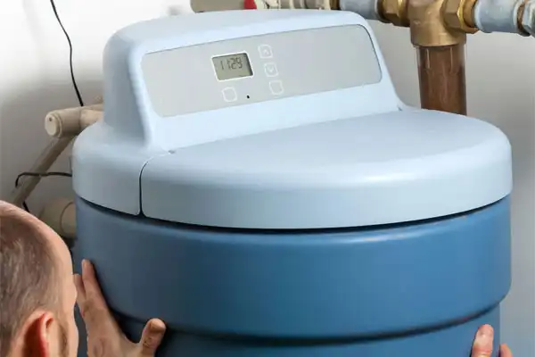 Person fine-tuning the cover of a water softener tank with a digital control panel, showcasing expert water softener installation skills.