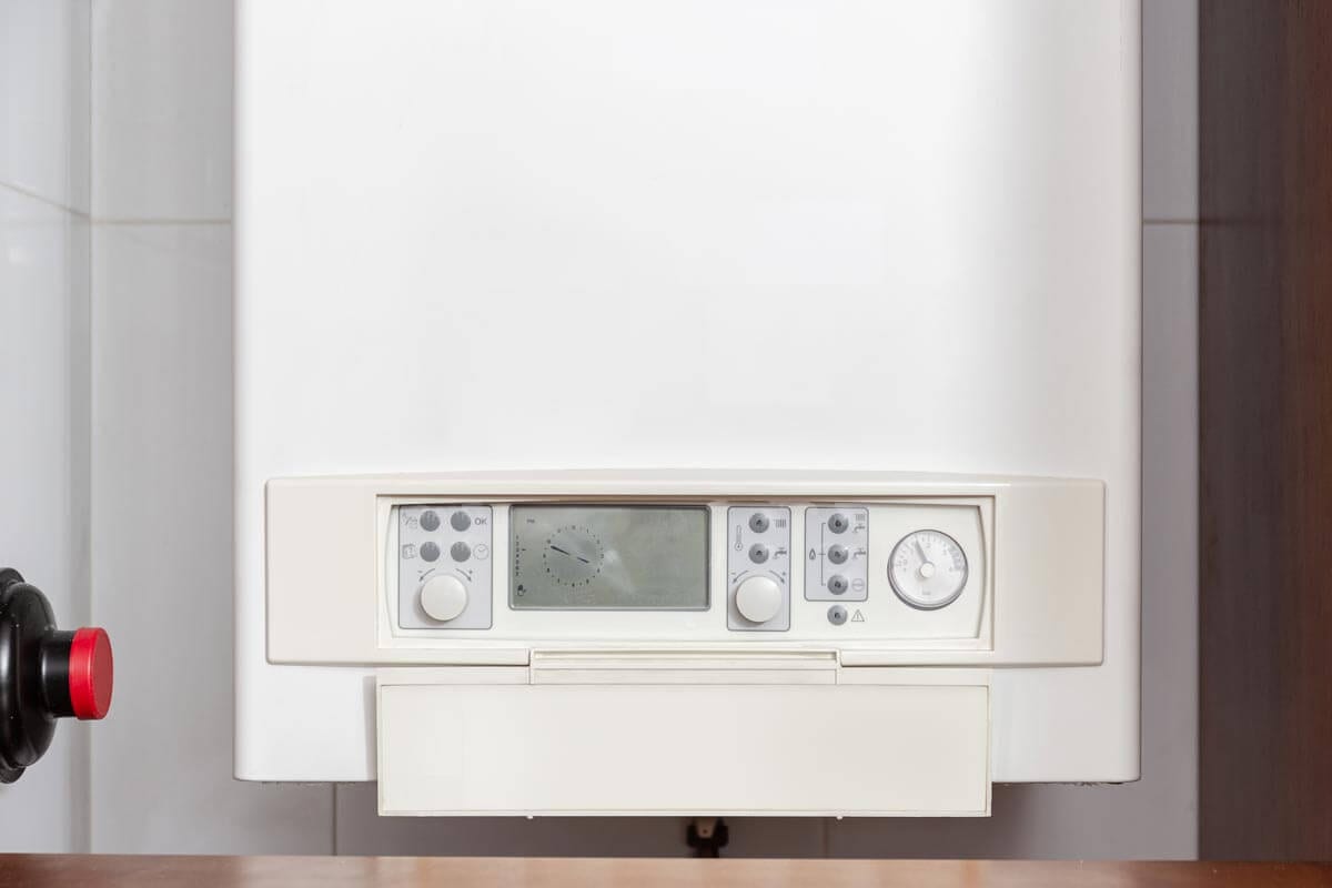 White boiler unit with control panel featuring knobs, buttons, a digital display, and a pressure gauge.